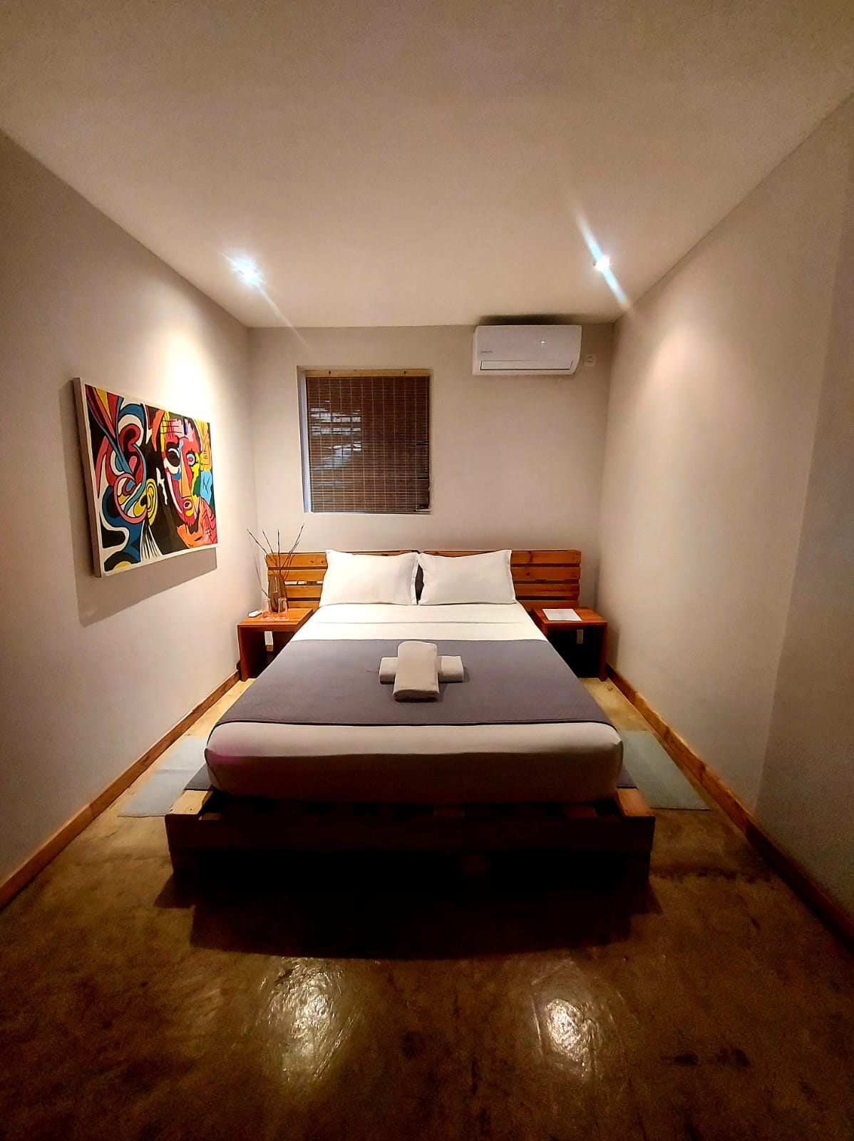 Quarto confortável com cama de casal e pintura abstrata